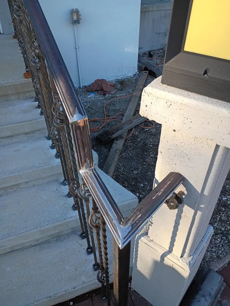 Curved metal handrail along the front steps of a porch