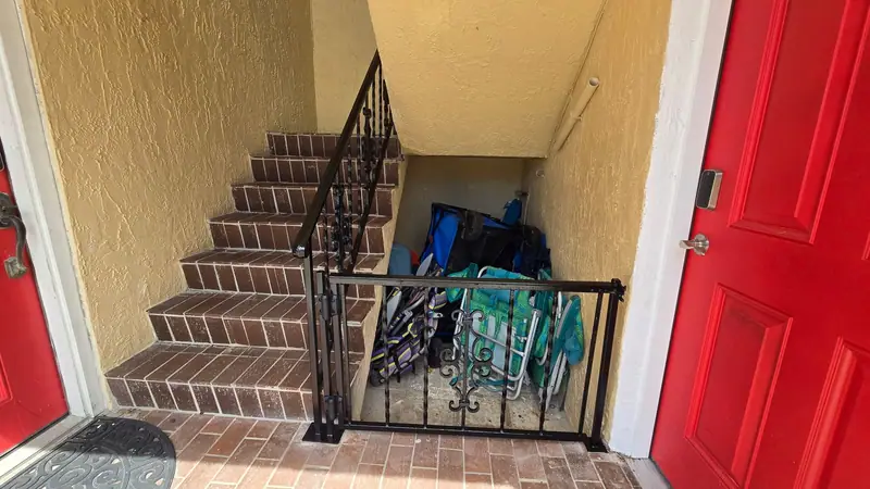 Black steel stair railing with scrollwork and a matching gate in a stucco stairwell