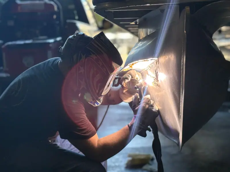 Haight Metal Worx welder TIG welding an aluminum pontoon tube, the arc lighting the seam